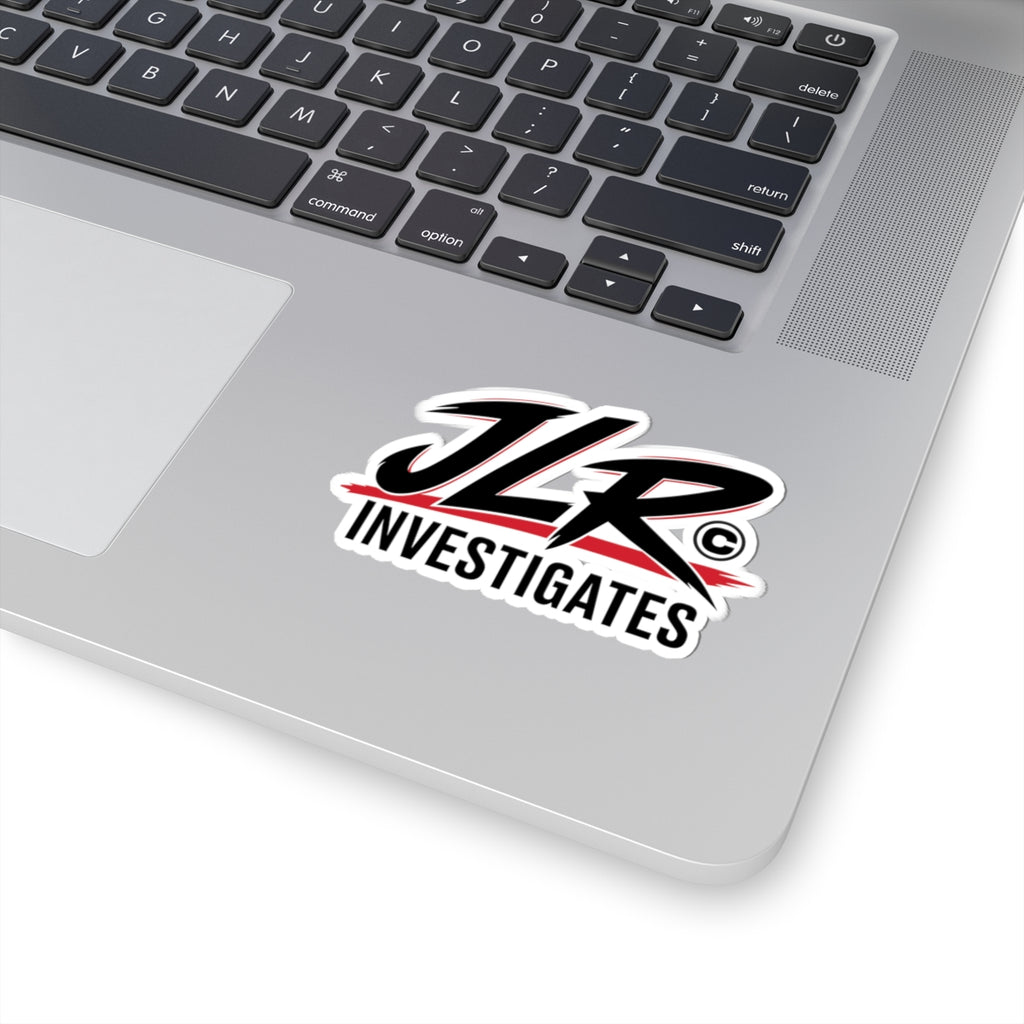 A die-cut sticker featuring the stylized text 'JLR INVESTIGATES' in black with red brushstroke accents and a white outline, shown on a laptop