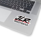 A die-cut sticker featuring the stylized text 'JLR INVESTIGATES' in black with red brushstroke accents and a white outline, shown on a laptop