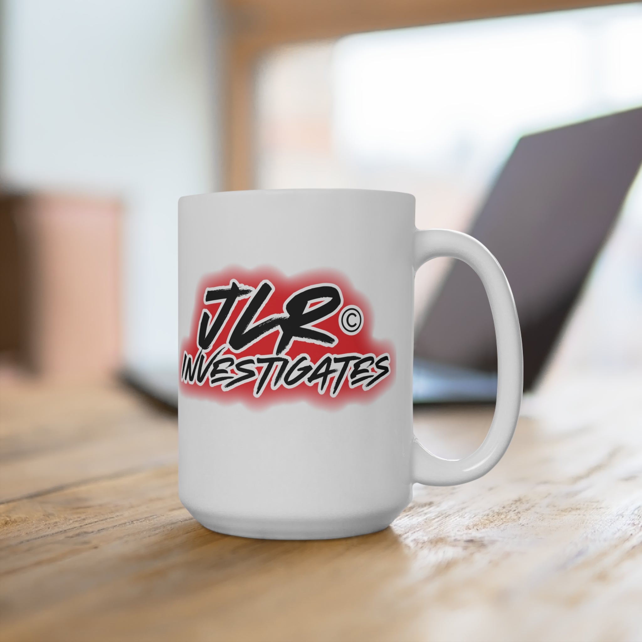 White mug with 'JLR Investigates' graffiti style logo on a white background on table