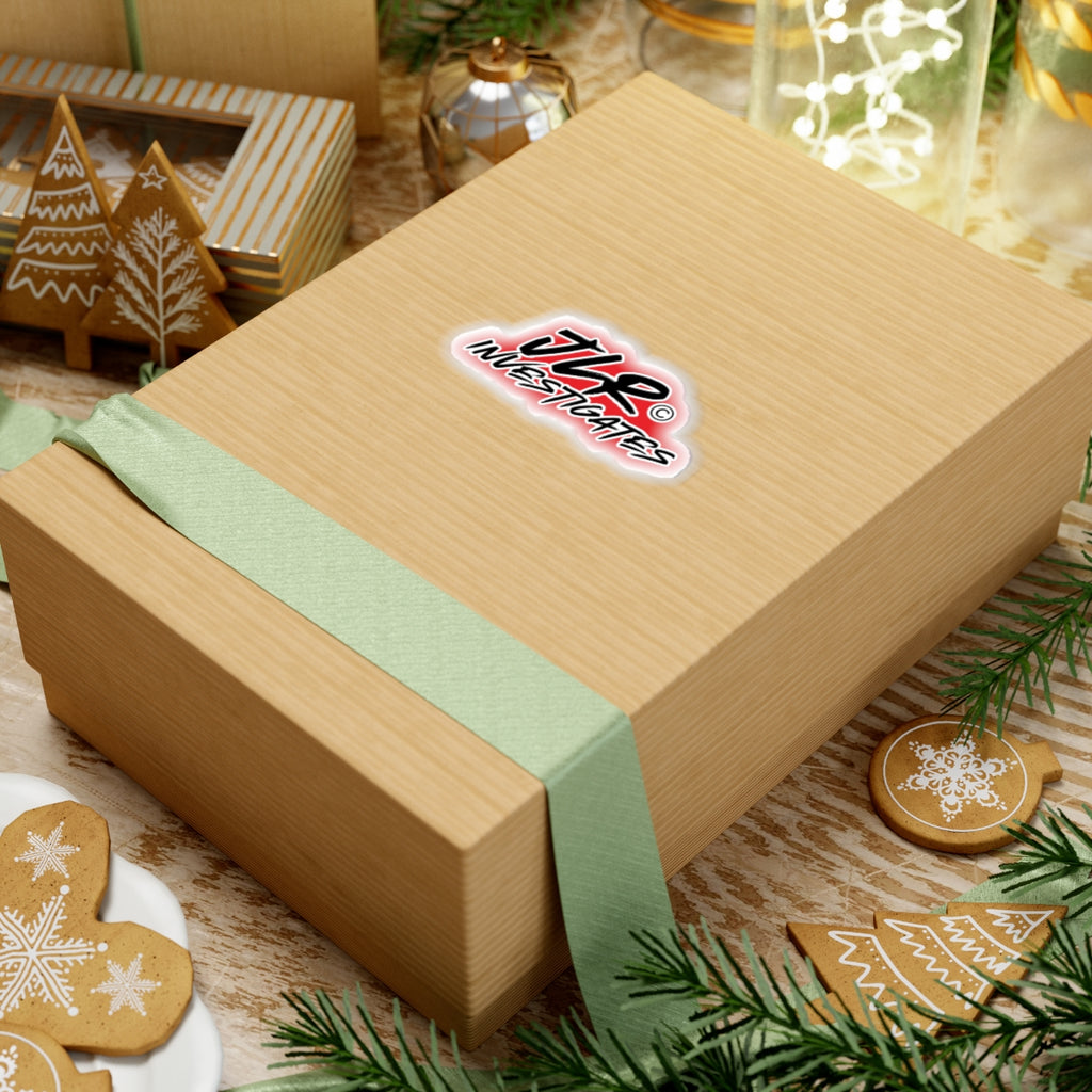 JLR© Investigates sticker on a cardboard shipping box surrounded by holiday greenery and ornaments