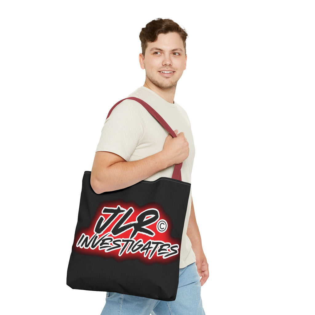 Man holding a black tote bag with red handle with 'JLR Investigates' logo on a white background