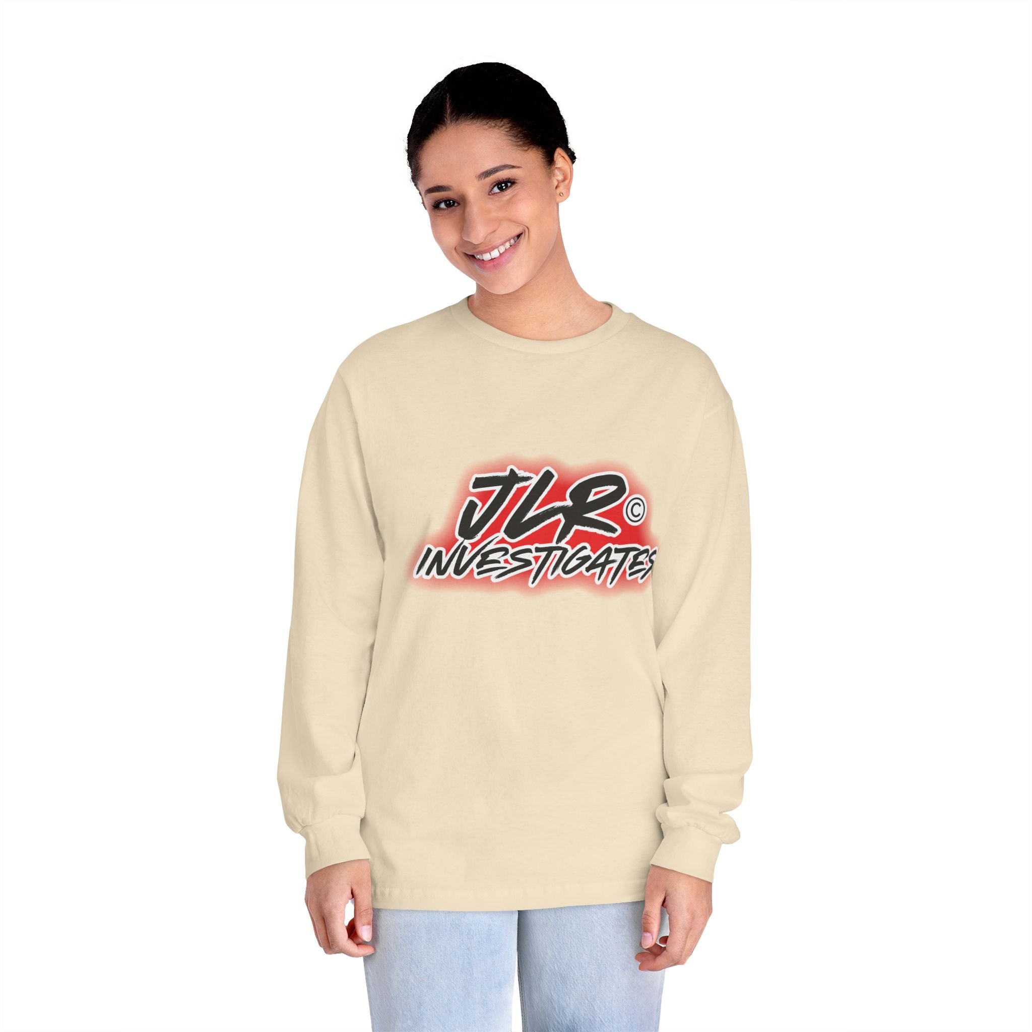 Woman wearing Sand long sleeve unisex t-shirt featuring bold 'JLR© Investigates' graffiti-style logo in red, white, and black