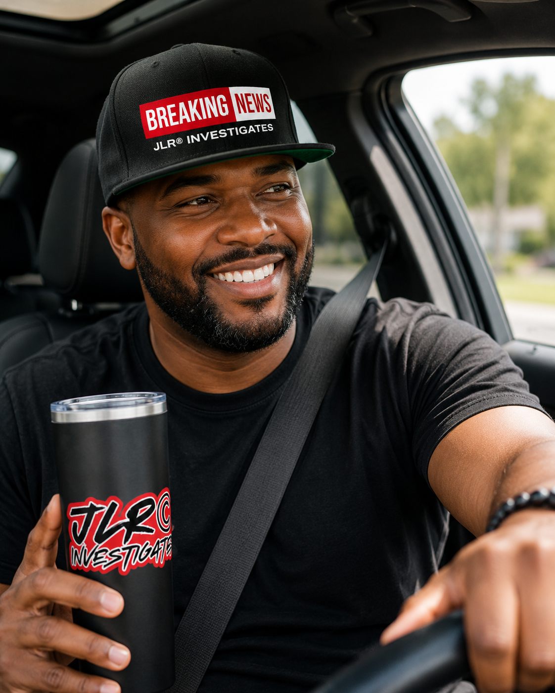 Man wearing a black "Breaking News" JLR® Investigates snapback hat while seated in a vehicle, holding a branded tumbler, lifestyle editorial shot