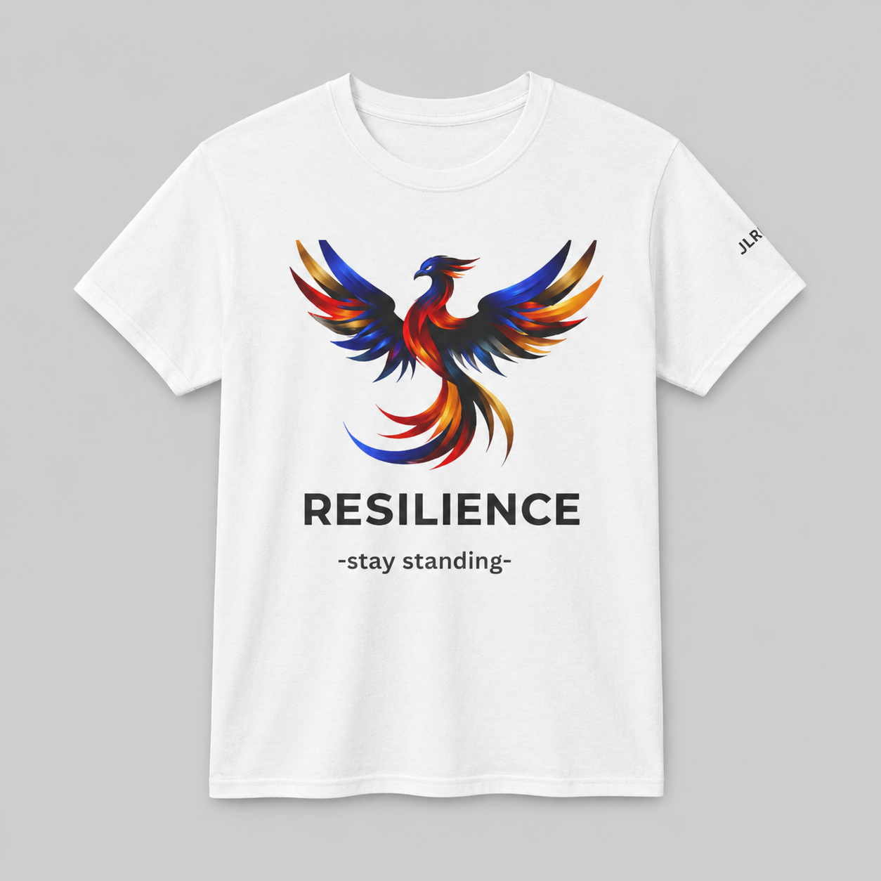 White unisex t-shirt featuring a bold multicolor phoenix rising graphic with the word RESILIENCE and tagline 'Stay Standing' — JLR Investigates apparel