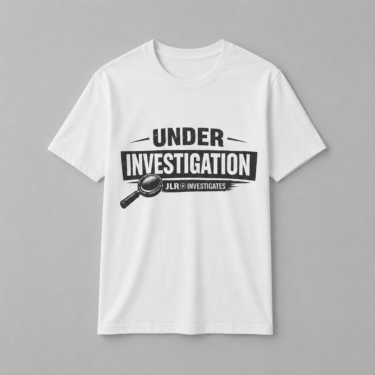 White unisex t-shirt featuring a bold 'Under Investigation — JLR© Investigates' graphic with a magnifying glass icon and black and white banner design