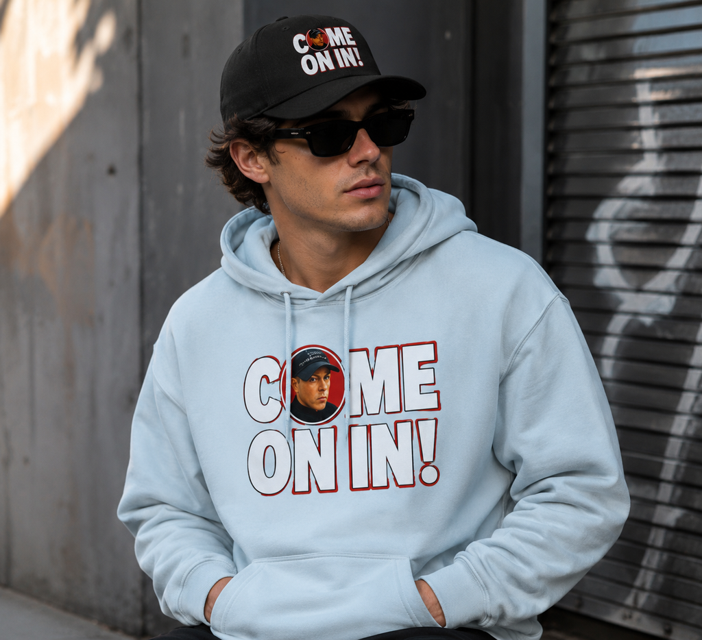 Young man wearing Blue Mist pullover hoodie featuring bold white 'COME ON IN!' text with a circular photo graphic replacing the letter O, printed on the chest