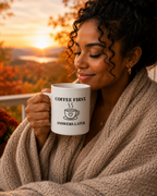 Woman holding a mug with 'Coffee First, Answers Later' text against a scenic background