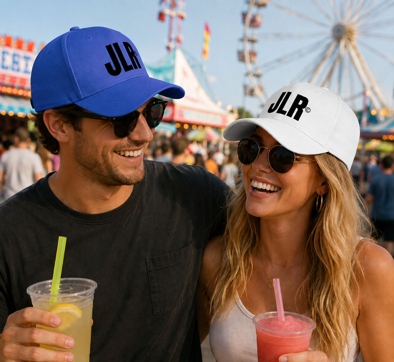 Couple at a fair wearing matching 'JLR' hats and holding drinks.
