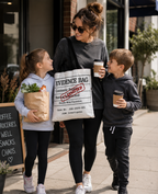 Woman and two children walking outdoors holding coffee cups and a bag labeled 'Evidence Bag'.