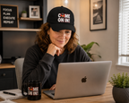 Person wearing the Come On In! JLR© Investigates Dad Hat with come on in coffee cup in Black while working at a laptop