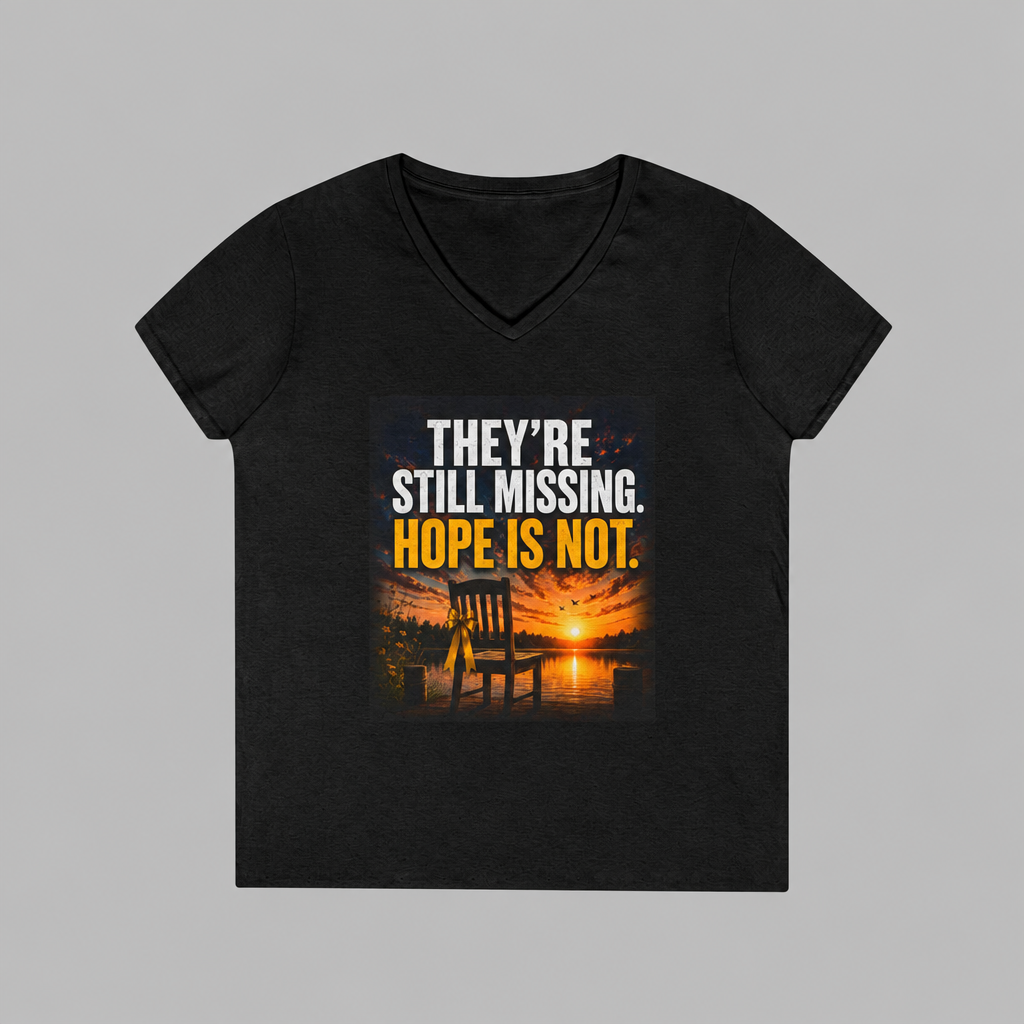 A black women's V-neck t-shirt with a graphic print on the front. The graphic features a sunset over water with an Adirondack chair, and the text 'THEY'RE STILL MISSING.